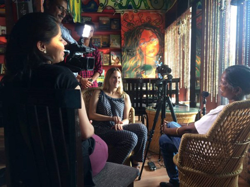 A group of diverse women and men filming a video in a room with paintings on the wall