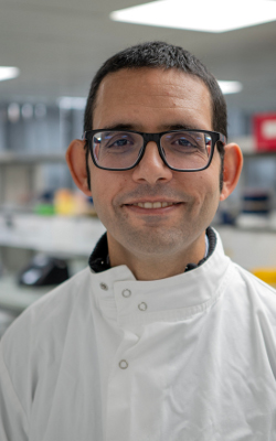 Francesco Crea, wearing glasses and a white jacket, looking at the camera