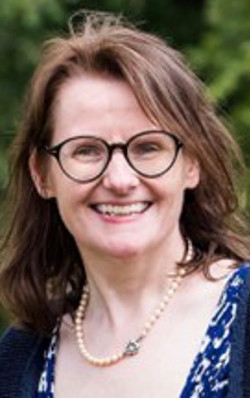 Grainne O'Connor, wearing glasses, looking at the camera
