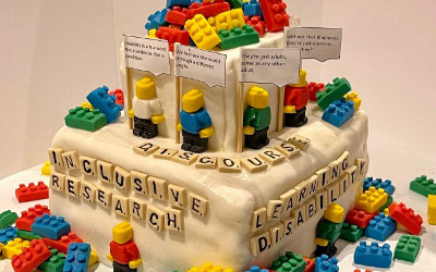 Square, white cake decorated with colourful lego figures and pieces
