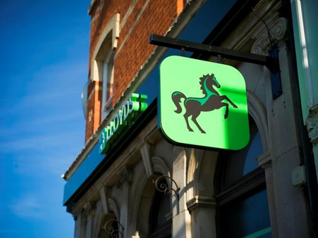 A Lloyds Bank building with the black horse logo sign hanging outside it