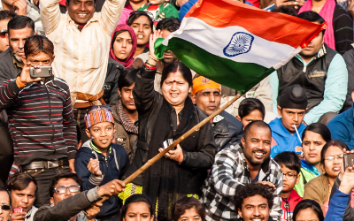 A crowd of Indian people, waving an Indian flag