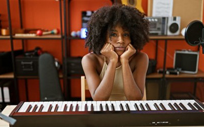 Woman sitting behind a keyboard, with her head resting in her hands, looking fed up