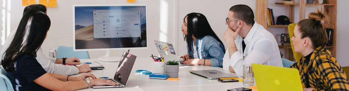 Group of people meeting round a table, looking at a screen on the wall