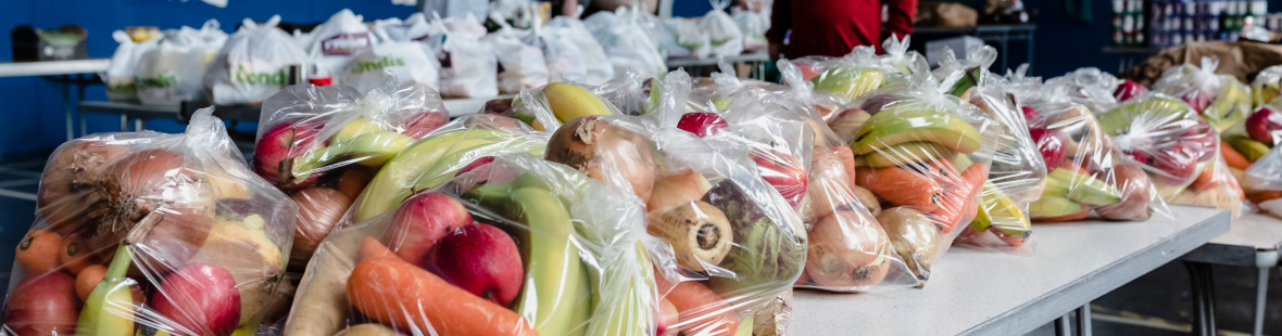 A foodbank, with bags of fruit and vegetables on a a table