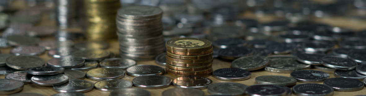 Coins spread across a table and stacked in piles