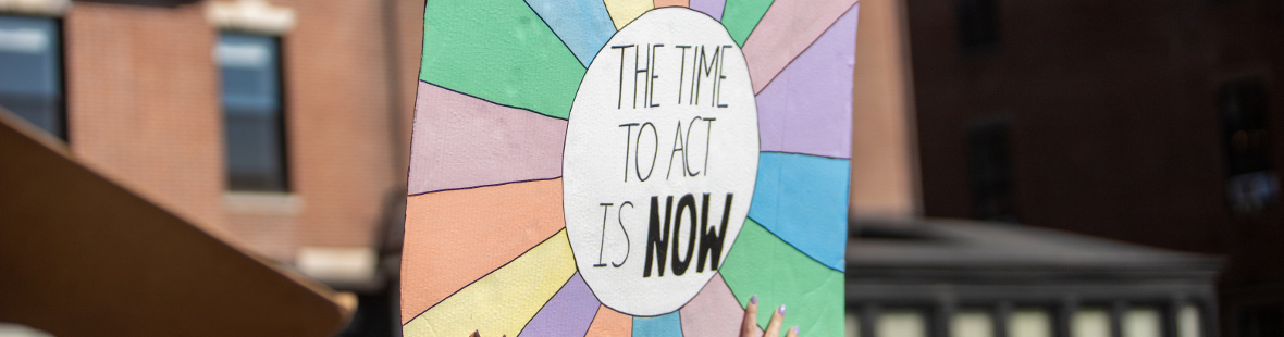 Person hold up a placard with the words 'The time to act is now' on it