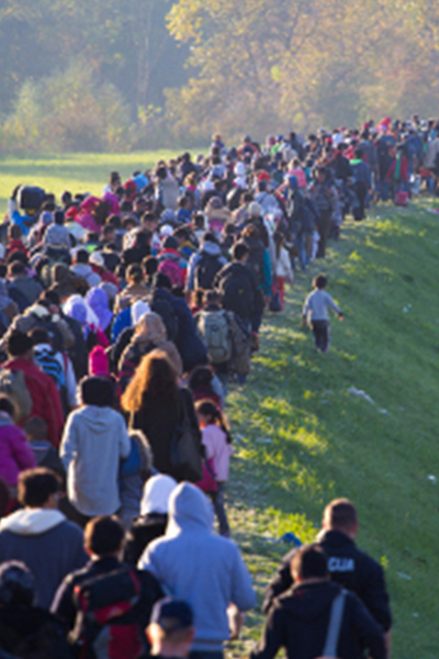 Migrants walking along a grass mound