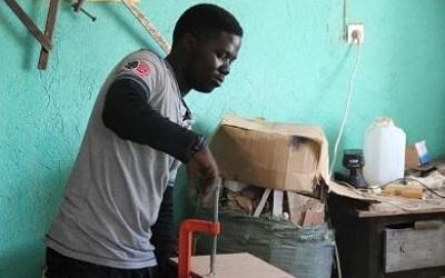 Photo of a young man of colour using tools to build 