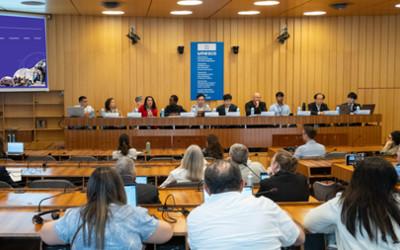 A panel of people sitting on a stage in front of an audience of people who are sitting at tables 