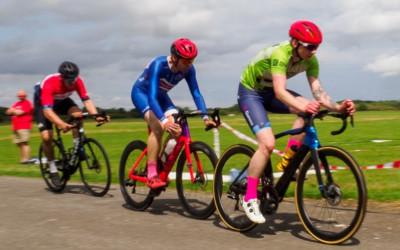 Three people in brightly coloured cycling clothes and wearing helmets, riding their bikes