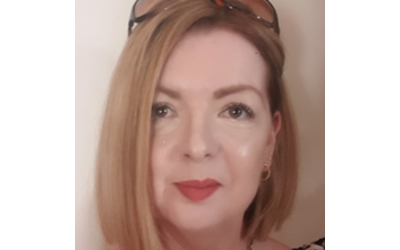 Carys Jennings, with light brown hair and a pair of glasses on the top of her head