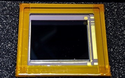 A square-shaped image sensor, with a gold outer edge and a black isquare inside the edge