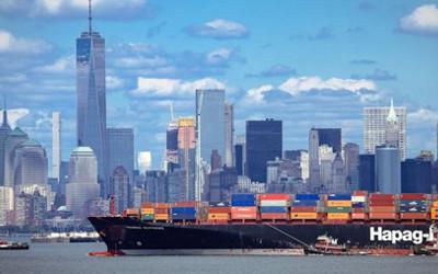 A container ship entering a port in New York with skyscrapers in the background