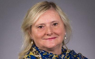 image of a blonde-haired woman with a blue, yellow and white scarf round her shoulders