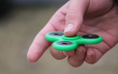 A green fidget spinner in a person's hand