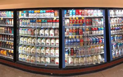 Supermarket chilled food cabinet filled with bottles of milk