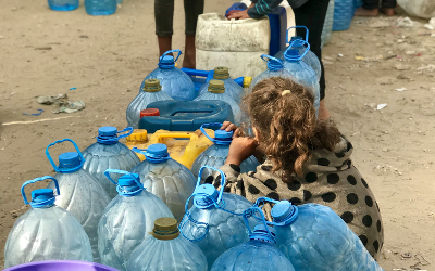 A little girl sitting next to water bottles in Gaza