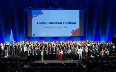 A group of people standing on a stage under a screen with the words 'Global Education Coalition' on it