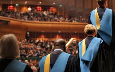 Group of students in graduation robes, queuing up to collect their certificate