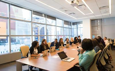 A diverse group of people sitting around a table with laptops in front of them