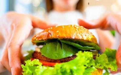 A close up of a hamburger in a bun with lettuce