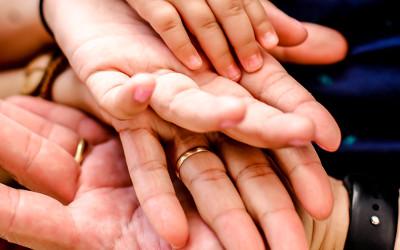 The hands of adults and children on top of each other