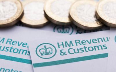 A few coins laid out in a row on top of papers with the words HM Revenue & Customs on them