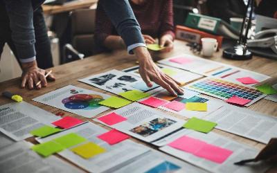 Man leaning over a table with papers and coloured sticky notes on it