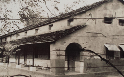 Long, white building surrounded by barbed wire