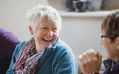 Two ladies sitting looking at each other and smiling