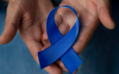 A blue prostate cancer ribbon in a person's hands