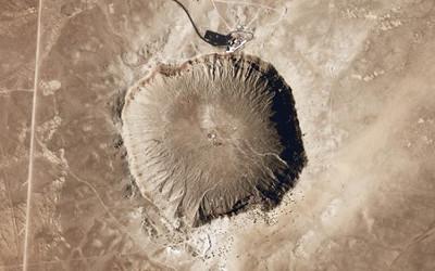 View from above of brown earth with a round crater in it