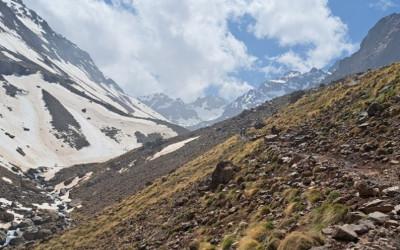 A view of grass and snow-covered mountains and a valley in between