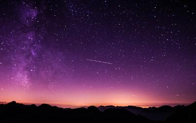 Purple night sky with stars above hills