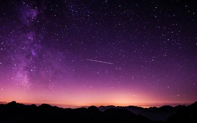 Purple night sky with stars above hills