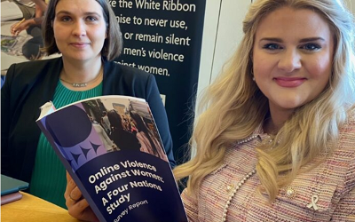 Olga Jurasz wearing a green top and blue jacket, with Alex Davies-Jones, wearing a pink top, looking at a copy of the Online Against Violence report