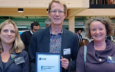 Two ladies and a man holding a certificate