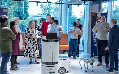 A group of people standing around talking and looking at robots