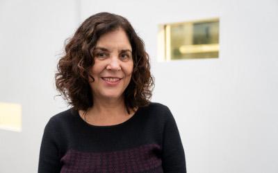 Rose Capdevilla, with shoulder-length, dark hair, wearing a dark top, looking at the camera