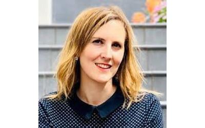 Dr Sara Calvo Martinez, with shoulder length dark blond hair, wearing a blue and white polka-dot blouse, smiling at the camera