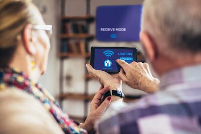 Elderly couple holding remote home control system