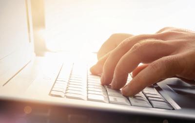 Man's hands typing on a laptop
