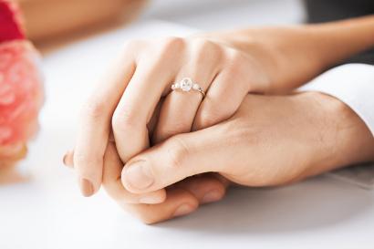Man and woman holding hands with wedding ring