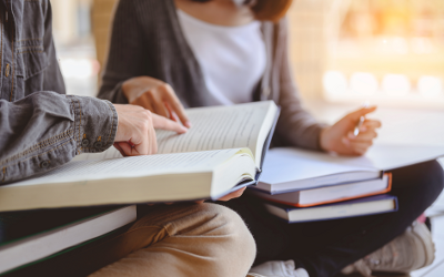 Two people sitting cross-legged on the floor reading books 