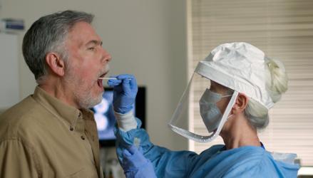 Man being tested for Covid-19 by healthcare worker in PPE 