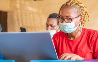 African students wearing facemasks and using a laptop