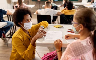 Teacher and young girl in a classroom wearing facemasks