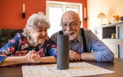 Senior couple, sitting at a table, using a virtual assistant