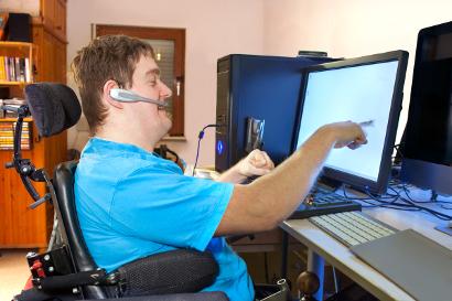 Young man with cerebal palsy on a computer